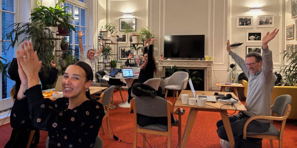 The EFN team are cheering after finishing an event. There is a mix of men and woman in a living room at desks and chairs.