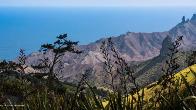A panoramic view of St Helena a rocky mountain with hills and scrubs under a blue sky
