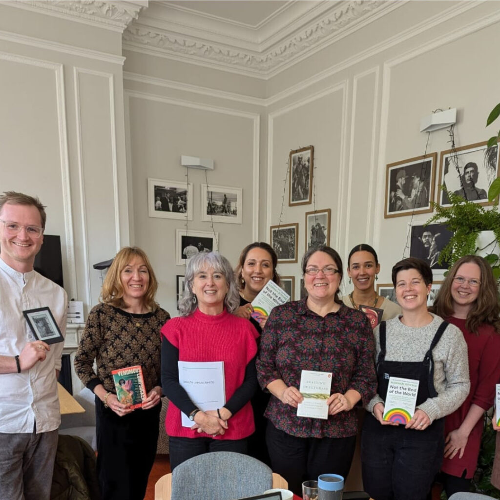 The EFN team - a group of women and one man - are holding books and smiling to camera in a group photo.