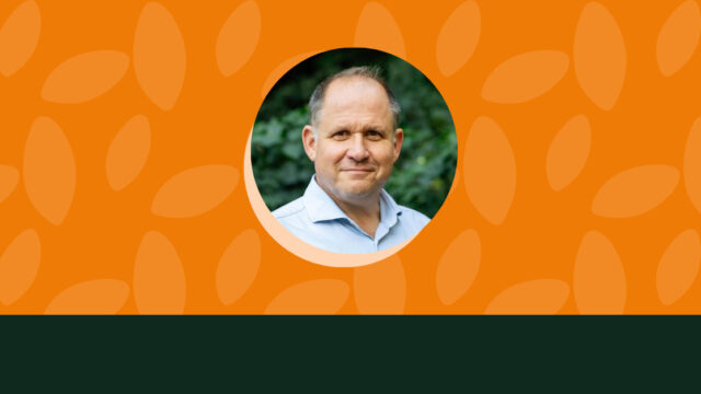 Henry Dimbleby, a white man wearing a blue collared shirt, is pictured outside against a green backdrop. The image of him appears in a small circle on top of an orange background.