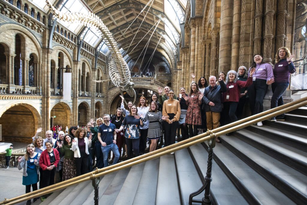 A group of fundraisers are standing on the stairs in the Natural History Museum in front of the blue whale.